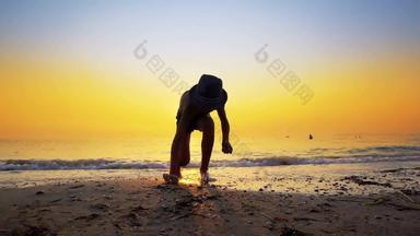 年轻的男孩他收集皮布尔斯海滩扔<strong>石头</strong>跳过游戏海日<strong>落水</strong>表面小夷为平地岩石跳跃水表面身体水次